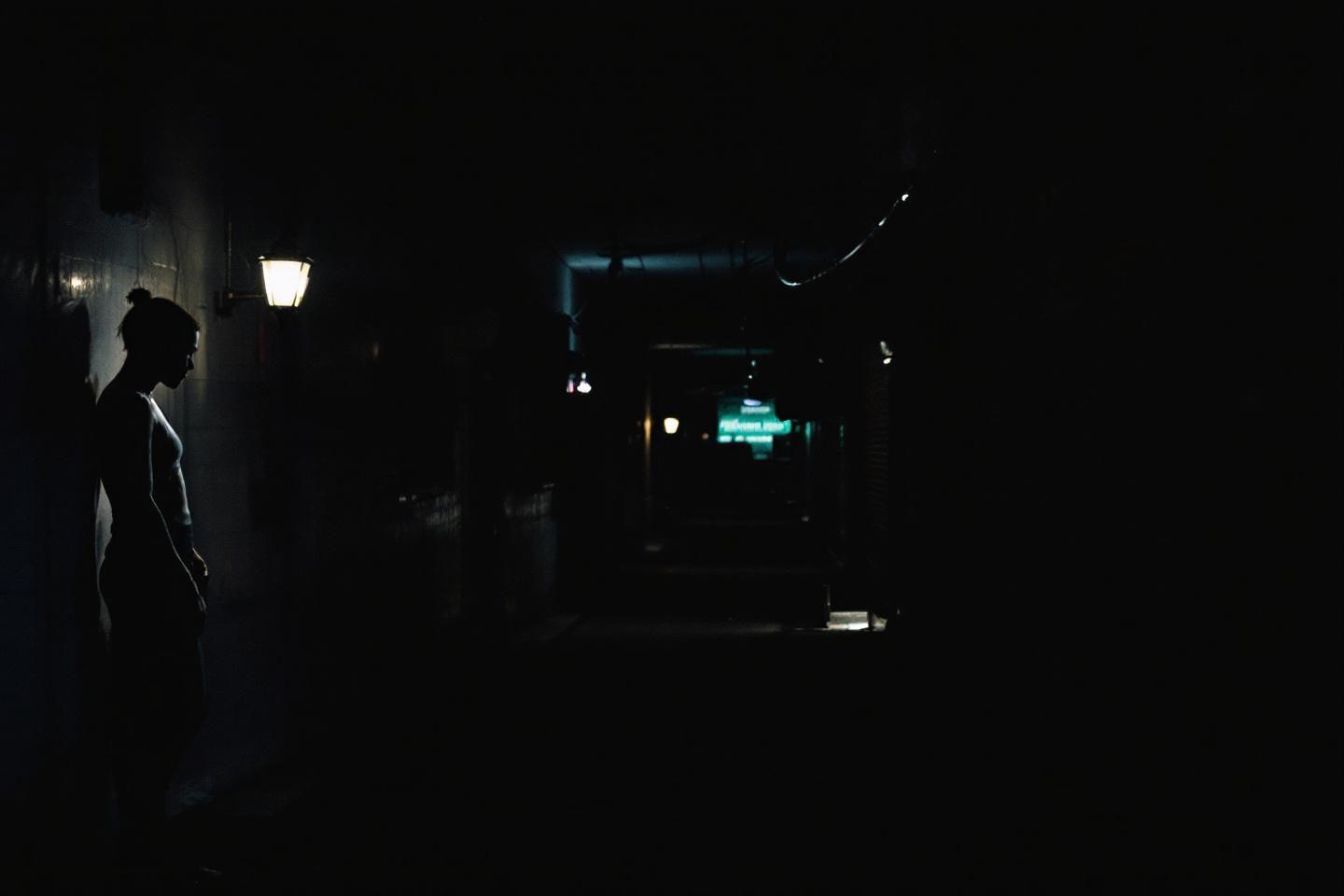 Forme sombre près d'un lampadaire dans une rue sombre
