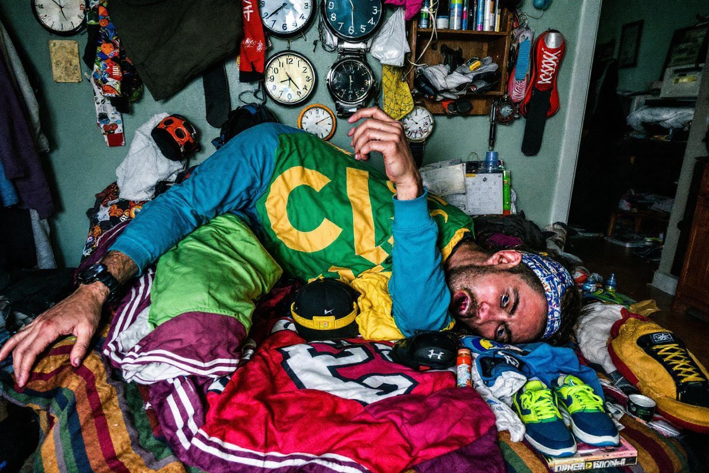 Homme endormi entouré de vêtements et horloges en désordre