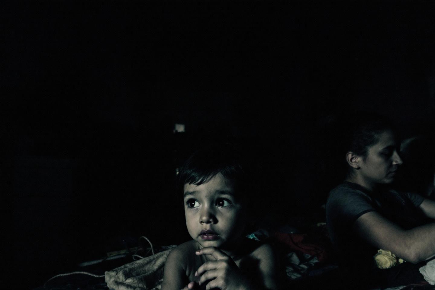 Jeune enfant aux grands yeux fixant l'obscurité silencieusement