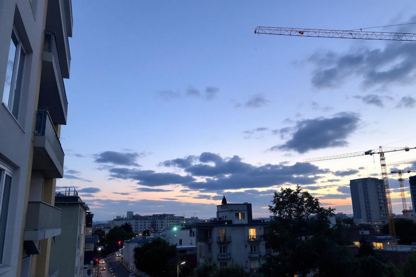 Vue sur une ville au cr&eacute;puscule avec immeubles et grues de construction