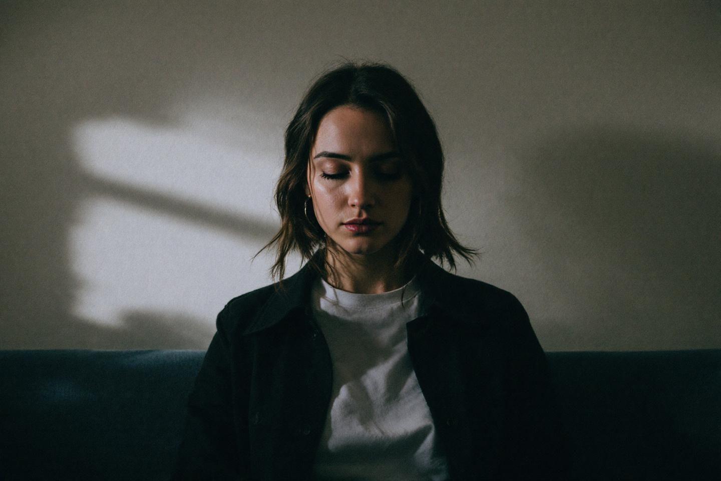 Femme en v&ecirc;tements sombres, regard baiss&eacute;, lumi&egrave;re diffuse