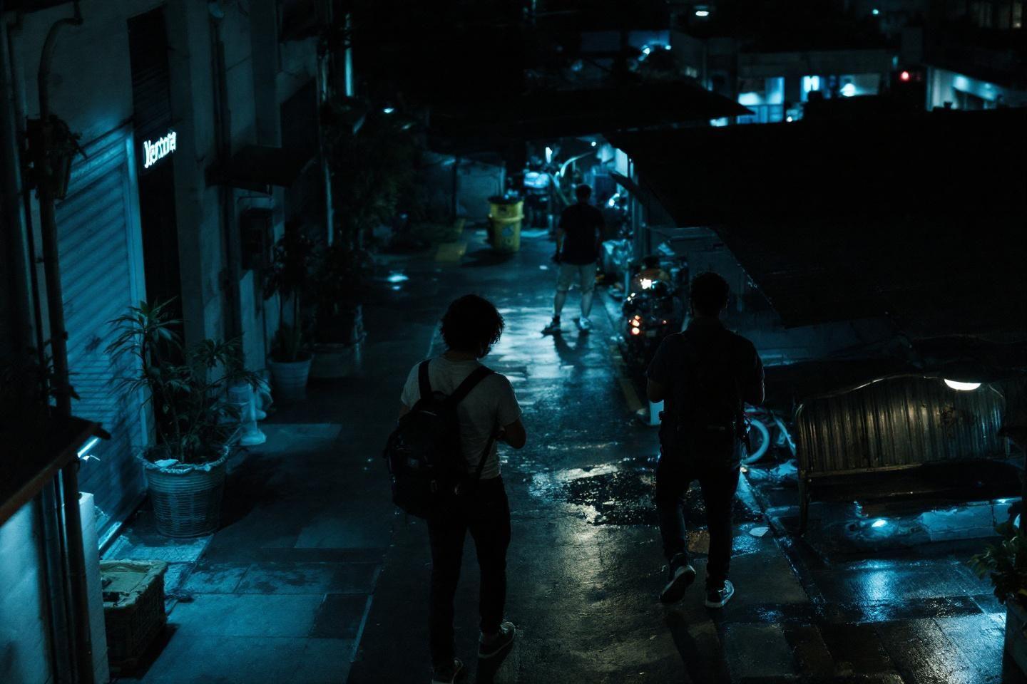 Deux silhouettes progressant dans une ruelle urbaine sombre