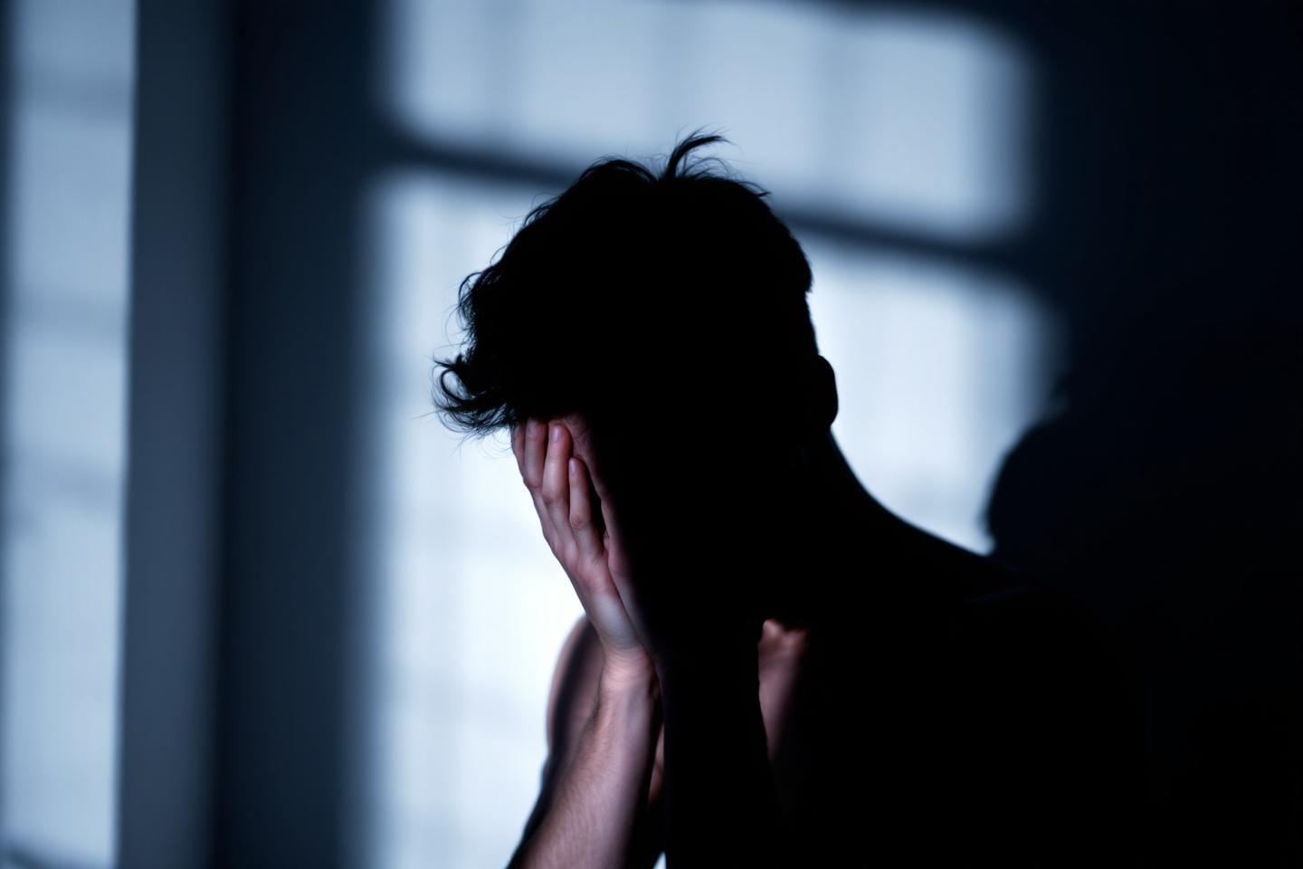 Silhouette sombre cachant son visage, lumière froide en arrière-plan
