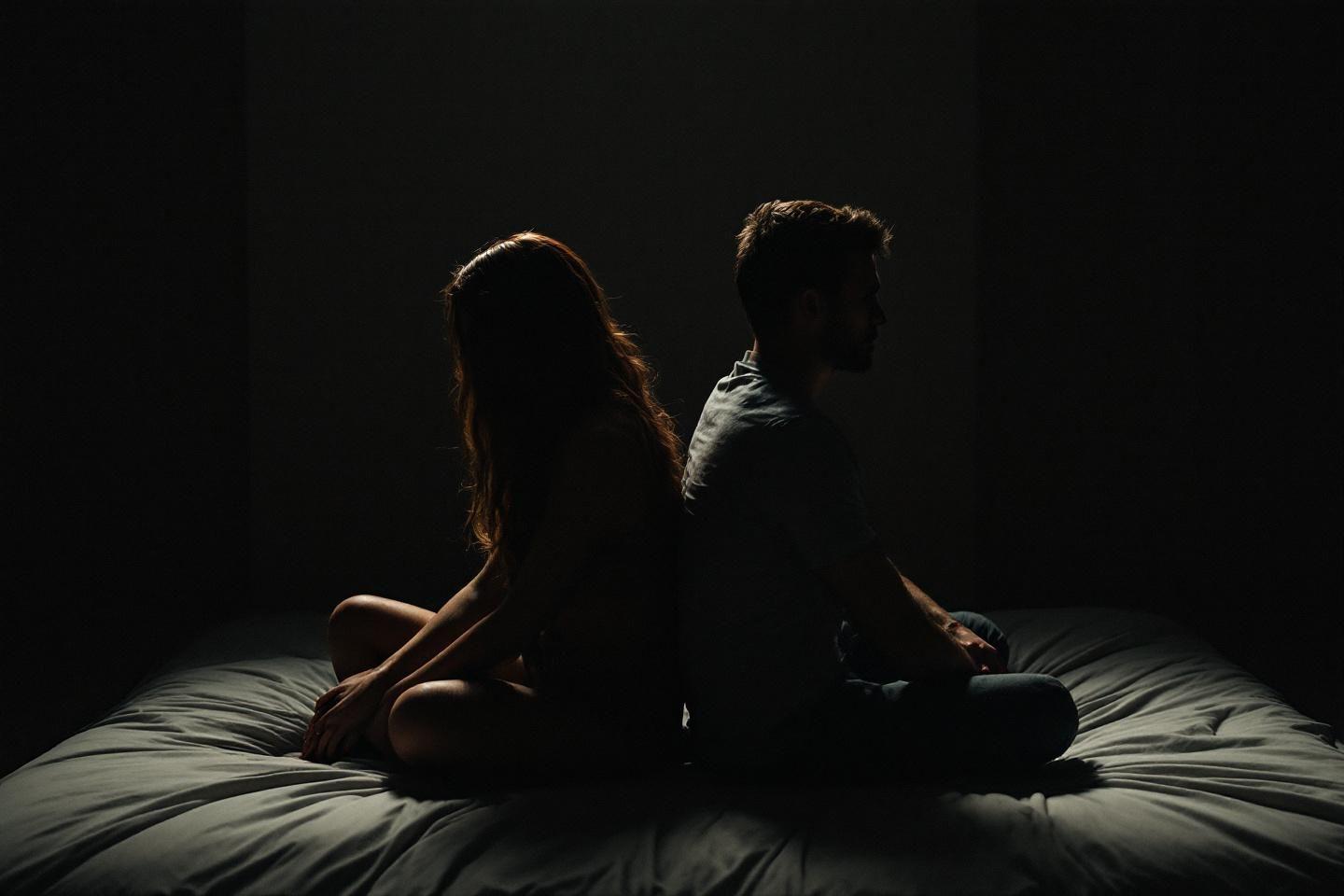 Deux silhouettes dos à dos dans une pénombre dramatique