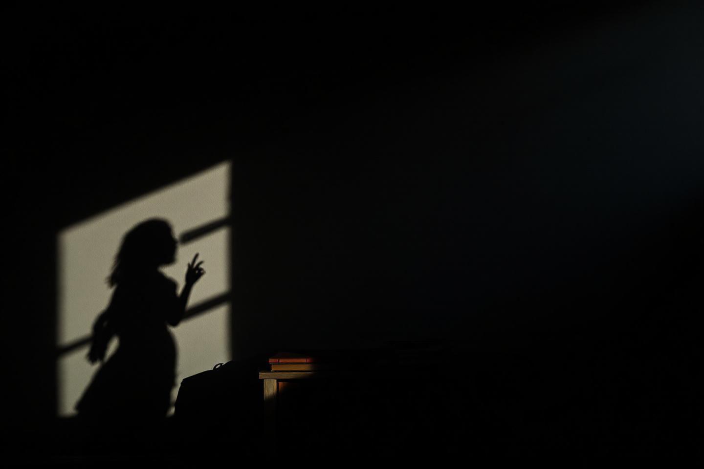 Silhouette sombre avec geste près d'une fenêtre éclairée