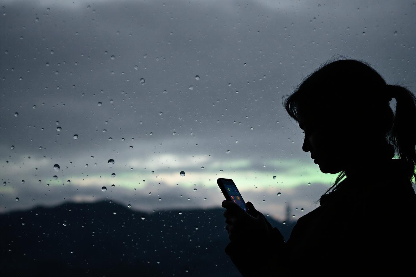 Un homme regarde attentivement son téléphone dans une pièce sombre