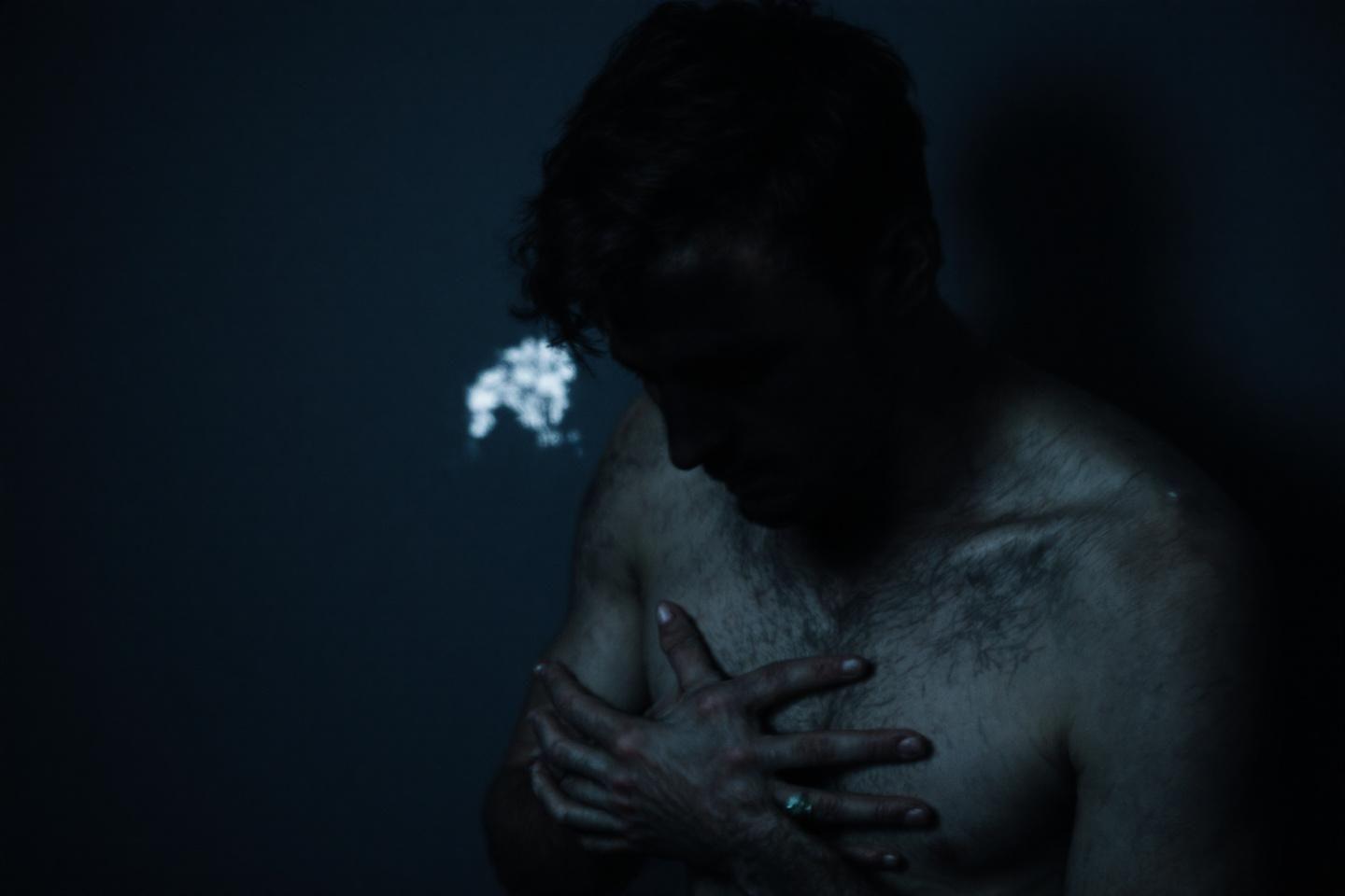 Forme humaine obscure avec éclat lumineux près de l'épaule