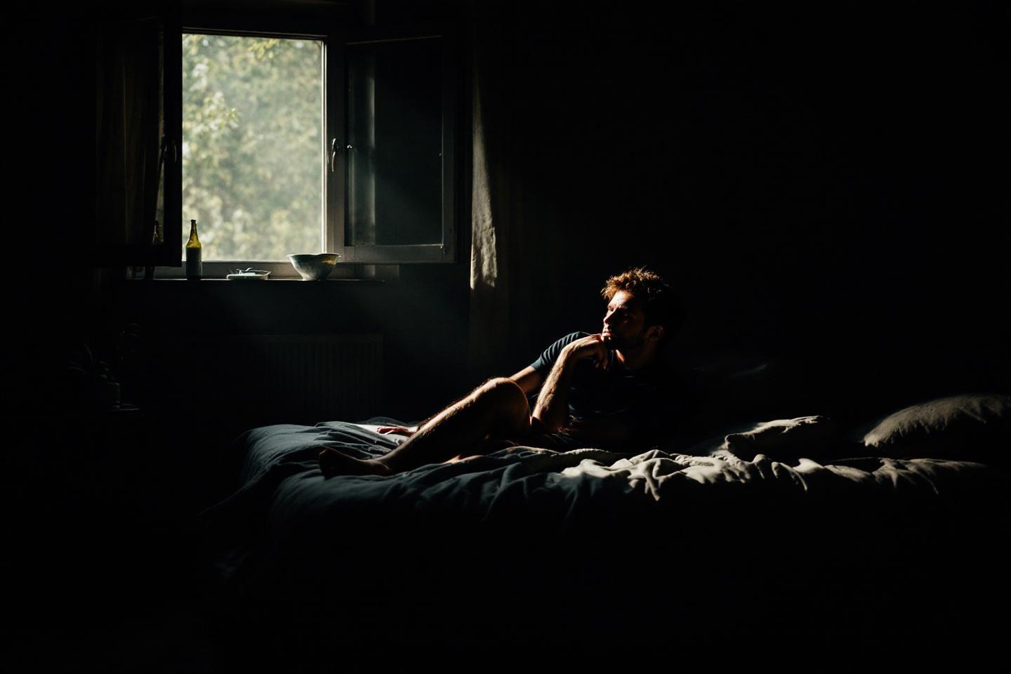 Silhouette sombre sur un lit près d'une fenêtre lumineuse